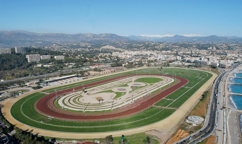 Vue d'ensemble d'un hippodrome et de ses différentes infrastructures : pistes, tribunes, corde, etc.